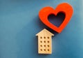 Wooden house and red heart on a blue background. Concept of sweet home. Property insurance. A new home for family. Family comfort Royalty Free Stock Photo