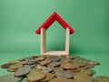 Wooden house on a scattering of coins on a green background Royalty Free Stock Photo