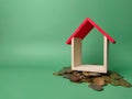 Wooden house on a scattering of coins on a green background Royalty Free Stock Photo