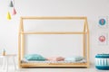 Wooden, house-shaped bed for a kid, pouf, table, lamps and ice-c