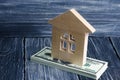 A wooden house stands on a stack of dolor banknotes. The concept of buying and selling immovability, rent of apartments.
