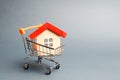 Wooden house in a Supermarket trolley. The concept of buying a house or apartment. Affordable housing. Profitable and cheap loans Royalty Free Stock Photo