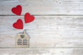 Wooden house with three red hearts on a wooden background. Love nest, love relationships. Buying a house with a young family. Royalty Free Stock Photo