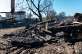 A wooden house in the village burned down because of a forest fire. Charred boards and various things lie on the ground, covered Royalty Free Stock Photo