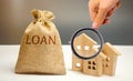 Wooden houses and a bag with the word Loan. Buying a home in debt. Family investment in real estate and risk management concept.