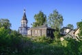 Wooden houses on a blooming meadow and the bell tower of Znamenskaya Church built in 1788 in the city of Pereslavl-Zalessky,