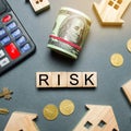 Wooden houses, a calculator, keys, coins and blocks with the word Risk. The risks of investing in real estate. The concept of Royalty Free Stock Photo