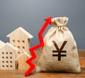 Wooden houses and a money bag with an up arrow. The concept of increasing the cost of housing. The growth of rent and mortgage Royalty Free Stock Photo