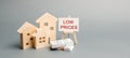 Wooden houses and a poster with the words Low Prices. The concept of reducing the value of real estate. Lower mortgage interest Royalty Free Stock Photo