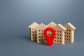 Wooden houses and a red location pin. Location, accessibility and proximity to infrastructure. Residential complex. City