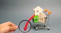 Wooden houses in a shopping cart and down arrow. Reduced interest in the mortgage. A decline in property prices and apartments.