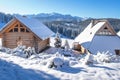 Wooden houses in snowy mountains on bright winter day. Snow and frost in mountain range in skiing season. Skiing resort guest Royalty Free Stock Photo