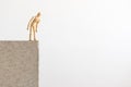 Wooden human figure standing on the edge of a concrete block, looking down Royalty Free Stock Photo