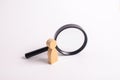 A wooden human figure stands near a magnifying glass Royalty Free Stock Photo