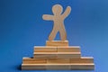 Wooden human figure on top of pyramid against background. Career promotion concept