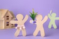 Wooden human figures fighting for attention of their beloved on lilac background. Jealousy concept