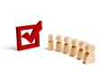 wooden human figures stand together next to a red tick in the box. The concept of elections and social technologies. Volunteers Royalty Free Stock Photo