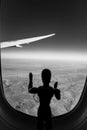 A Wooden Human Manikin standing looking through an airplane window at the landscape below