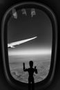 A Wooden Human Manikin standing looking through an airplane window at the landscape below
