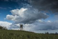 Wooden hunter high seat on field with heavy clouds