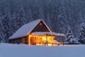 Wooden hut on the lawn covered with snow. The lamps light up the house at the evening time. Winter landscape. Mystical night. Royalty Free Stock Photo