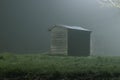 A wooden hut lit by street lights, on a moody, atmospheric, foggy winters night