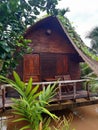 Wooden hut among lush vegetation on murky waters of the Mekong. Rustic bungalow entrance detail. Asian architecture and