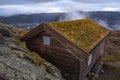 Wooden hut on the mountain stones. Moss on the roof. Fog over the city in Norway Royalty Free Stock Photo