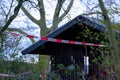 A wooden hut in a public park is cordoned off by police crime scene tape