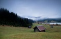 Wooden huts and fog over Geroldsee lake in dusk