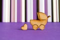 Wooden icon of baby carriage and little heart on purple striped