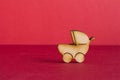 Wooden icon of baby carriage on red background