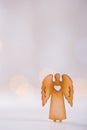 Wooden icon of Christmas angel with hole in form of heart on light bokeh background