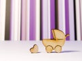 Wooden icons of baby carriage and heart on a white surface and p