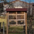 Wooden insect hotel in front of a wooden farmhouse
