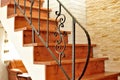 Wooden interior stairway with ornamental ironwork railing Royalty Free Stock Photo