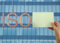 Wooden ISO text Stands for International Organization for Standardization hanging on rope and businessman hold a green paper. Royalty Free Stock Photo