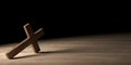 Wooden Jesus Christ christian crucifix or cross leaning on wood table with spotlight on black background with copy space, god,