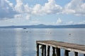 Wooden jetty for boats against a blue sky with some clouds. Floating buoys. Hills on background. Bolsena lake, Italy Royalty Free Stock Photo