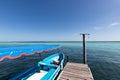 wooden jetty for boats on a blue and blue crystalline Caribbean sea with a moored blue boat . Caribbean fishing boat with a Royalty Free Stock Photo