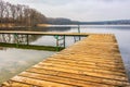 Wooden jetty at the lake surrounded by trees. Autumn landscape and reflection in the water. Royalty Free Stock Photo