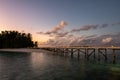 Wooden jetty with lanterns over the ocean extending from tropical island, with blurred water and sunset in the background, Royalty Free Stock Photo