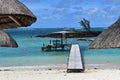 Wooden jetty over the Indian ocean, view between huts on a white sand beach.