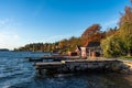 Wooden jetty pier on old stones base. Cabins small holiday cottages red houses on the shore. Beautiful autumn view of rocky and Royalty Free Stock Photo