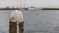 Wooden jetty pole with metal on a pier on a lake with calm waters and a boat in the background Royalty Free Stock Photo