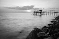 wooden Jetty with the rocky seaside during sunset. Landscape Orientation Black and White Royalty Free Stock Photo