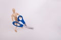 Wooden jointed manikin holding craft scissors on a solid background Royalty Free Stock Photo