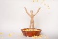 Wooden jointed mannequin doll standing in popcorn bowl throwing popped corn kernels in the air