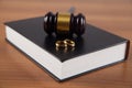 Wooden judge gavel, book and golden rings, divorce concept Royalty Free Stock Photo