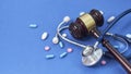 Wooden judge gavel with drugs on table. Space for text. Medical concept. on a blue background. expired drugs. fake